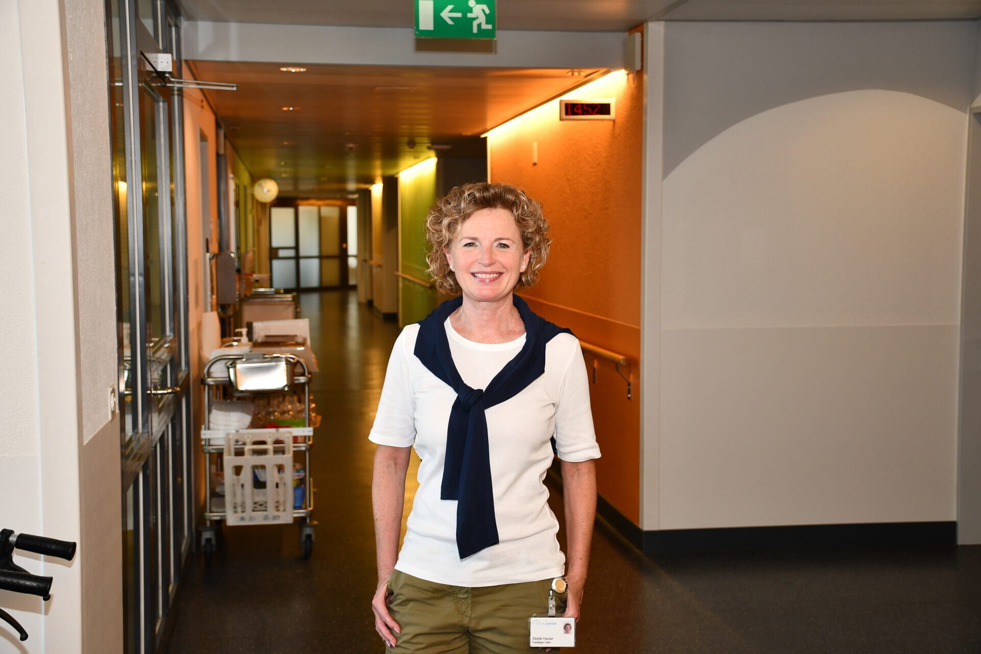Dame des Freiwilligen-Teams steht im Spitalkorridor