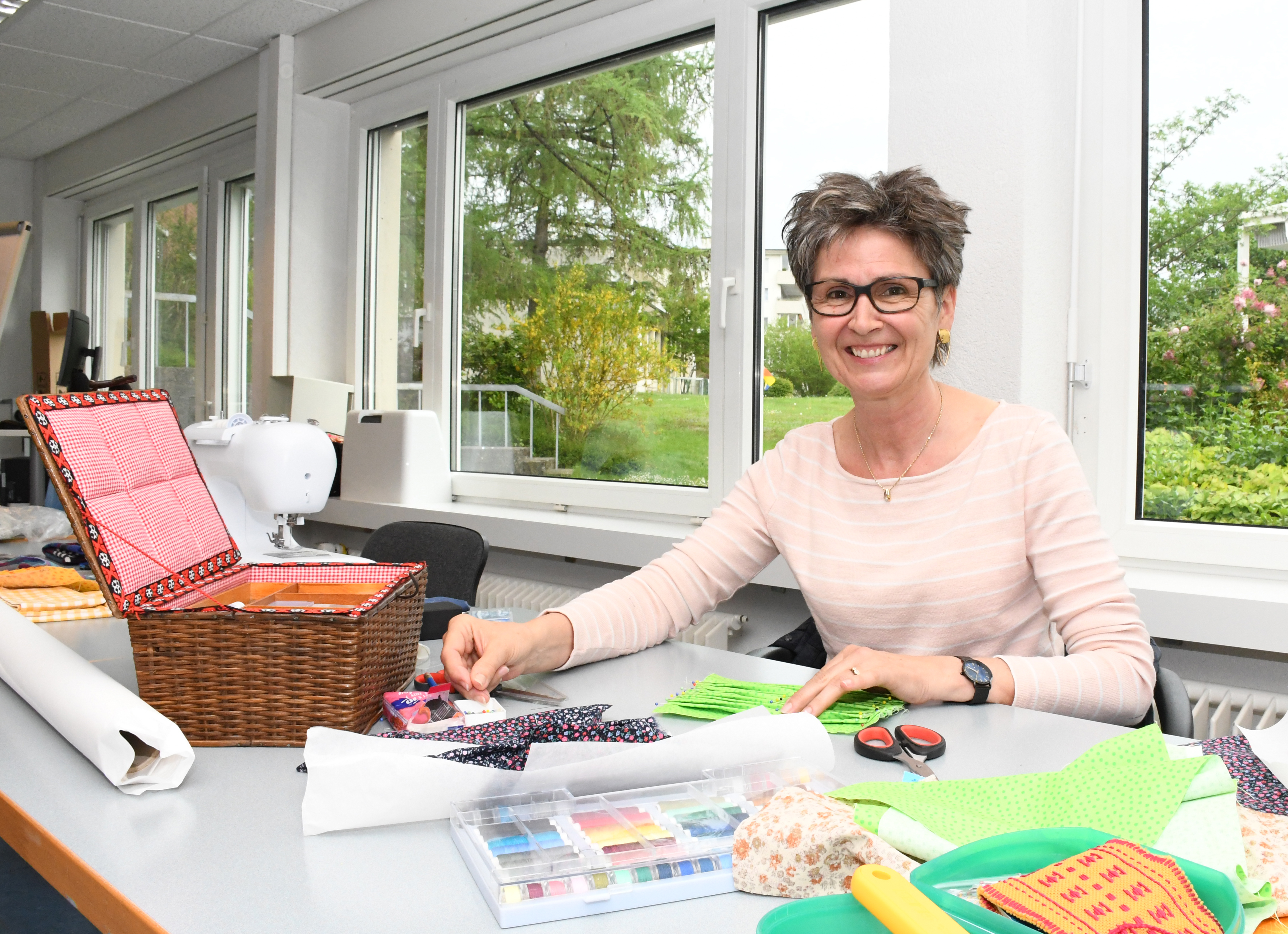 Silvia Schaufelberger sitzt am Tisch und näht eine Nesteldecke