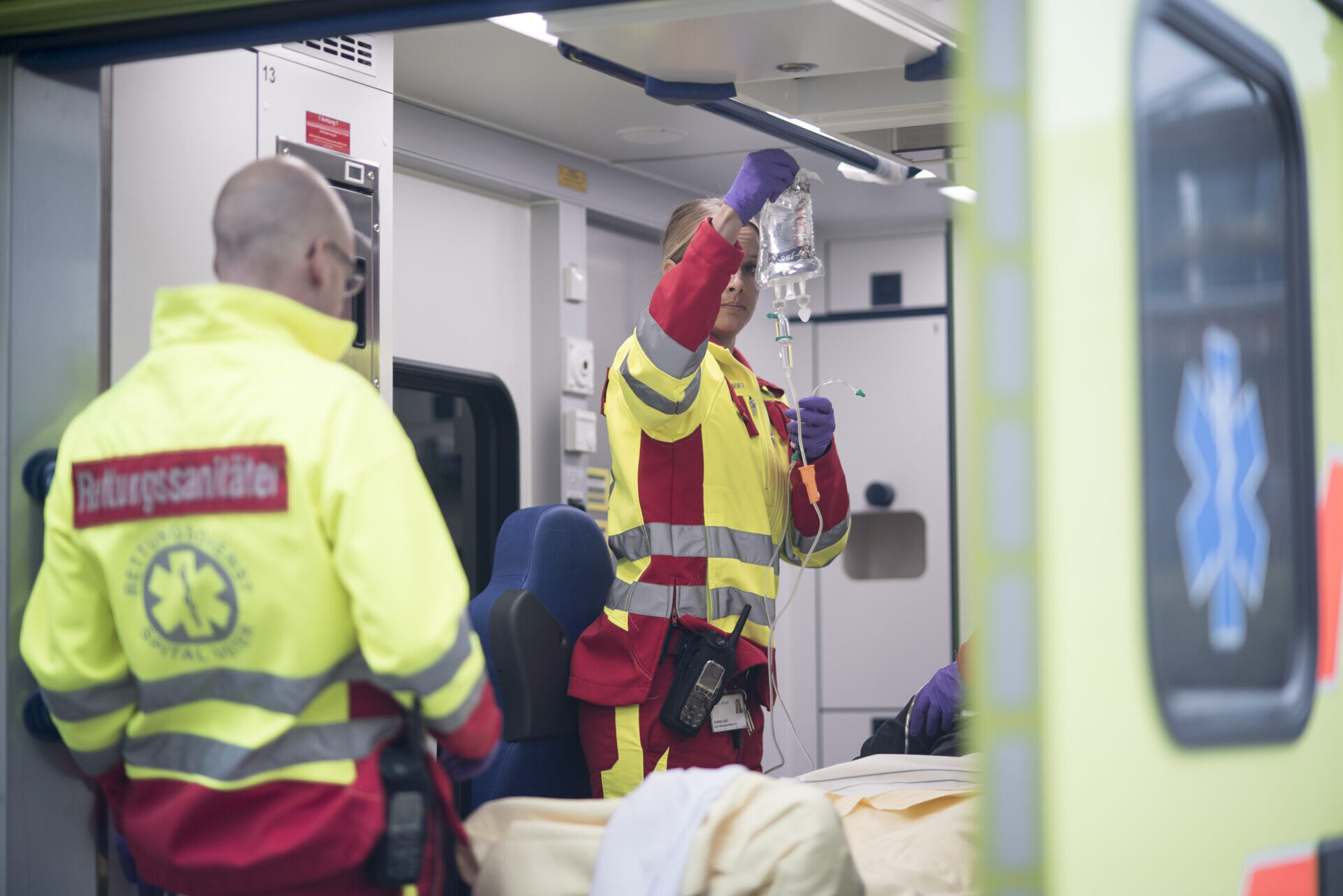 Zwei Mitarbeitende auf der Rückseite bzw. im Innenbereich des Rettungsfahrzeuges